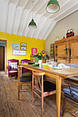 Dining room with yellow wall, wooden table and leather armchairs