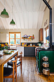 Country-style kitchen with green oven, dining area and pendant lights