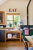 Landhausküche mit Holztheke und "EAT"-Schriftzug über dem Fenster