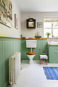 Toilette in Badezimmer mit Holzvertäfelung in Grün, weißem Boden und maritimer Dekoration