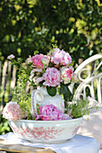 Bouquet of peonies in nostalgic vase on garden table