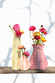 Ranunculus in glass vases covered artistically with paper in various vase shapes