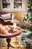 Runder Tisch mit Kerzen und Kaffeetasse in weihnachtlich geschmücktem Wohnzimmer