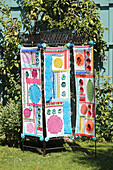 Screen decorated with doilies, trims, crochet flowers and pompoms in the garden