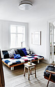Sofa mit buntem Patchwork-Bezug und Holzhocker in hellem Wohnzimmer