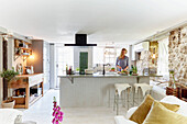 Woman in open country-style kitchen with large island and natural stone wall