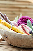 Colorful carrots and vegetables in a rustic wooden bowl on a wooden table