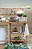 Regal aus Bambus mit Kochbüchern, Lebensmitteln und Kräutern auf Balkon