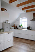 Helle Küche mit weißer Einrichtung im Landhausstil mit Holzbalkendecke