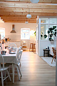 Essbereich mit weißem Tisch und Holzstühlen im skandinavischen Stil mit Blick in die Küche