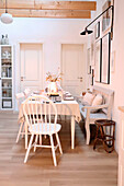 Essbereich im skandinavischen Stil mit weißem Holztisch, Stühlen und Sitzbank