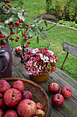 Hydrangea bouquet and red apples on garden table