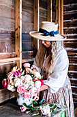 Woman with a lush bouquet of roses in front of a wooden wall