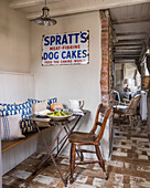 Cosy corner with covered dining table and vintage advertising sign in rustic kitchen