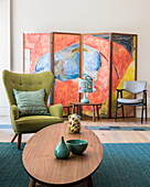 Wohnzimmer mit olivfarbenem Sessel und Triptychon mit abstraktem Muster