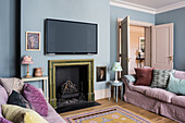 Living room in pastel colors with fireplace and wall-mounted TV