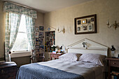 Double bed with patterned bed linen in traditionally furnished bedroom