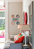 Wohnzimmer mit dekorativen Wandtellern und farbenfrohen Kissen auf grauem Sofa