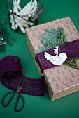 Christmas gift decorated with jute, fir twigs and pigeon shaped pendant