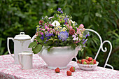 Romantisch gedeckte Kaffeetafel im Mai, mit Wiesenblumenstrauß, Erdbeeren und Kaffeegeschirr