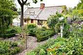 View of the garden with cobblestone paths and the house
