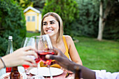 Freunde stoßen mit Wein auf ein Sommeressen im Garten an
