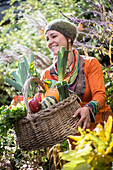 Frau sammelt Obst und Gemüse, während sie im Garten steht