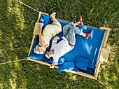 Elderly couple lying on swing bed, watching drone