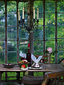 Old wooden table with cake and berry juice, above candlestick chandelier in the greenhouse