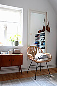 Moderner Rattanstuhl und Vintage-Holzkommode in hellem Ankleidezimmer