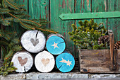 Logs decorated with Christmas motifs, conifer branches and pine cones in wooden box