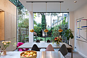 Offene Küche mit Mittelblock und Essbereich, Blick durch Verglasung in den Garten