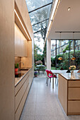 Open-plan kitchen with island counter, dining area, glass roof and garden view