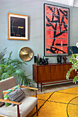 Sideboard with decorative objects, above it modern art and wall lamp in the living room