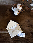 Eine Dankeskarte mit versandfertigen Umschlag und Baumwollblüte auf Holztisch