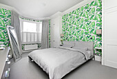 Bedroom with green jungle wallpaper and grey bed linen