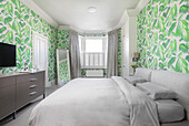 Bedroom with jungle wallpaper and grey bed linen