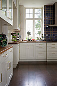 Classic fitted kitchen with white cupboards and wooden worktop