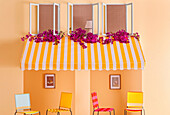 Yellow and white striped awning over colourful chairs
