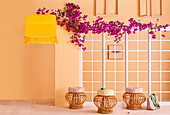 Rattan stools with cushions in front of mullioned windows with bougainvillea