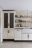 Spülbecken mit Abtropffläche, darüber Geschirrregal und Doppelschrank mit oberen Türen aus perforiertem Zink in der Küche