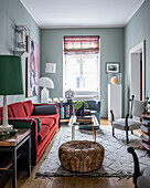 Rotes Samtsofa, Lederpouf, und andere Sitzmöbel im Wohnzimmer mit blaugrauen Wänden