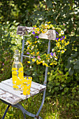 Wreath of flowers on old wooden chair with lemonade bottle and glass in the garden