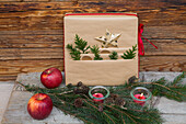 Gift made from natural wrapping paper, fir branches, apples and tea lights