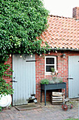 Red brick wall with blue door and plant shelf in the outdoor area