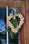 DIY door wreath made from peanuts with green branches and ribbon