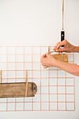 Hands attaching wooden box to copper grid on white wall