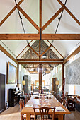 Long dining table in converted barn with open ceiling structure