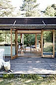 Blick über Holzterrasse ins transparente Haus