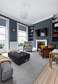 Upholstered furniture and leather armchairs in the living room with grey walls